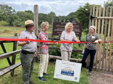 People cutting ribbon at garden opening ceremony.