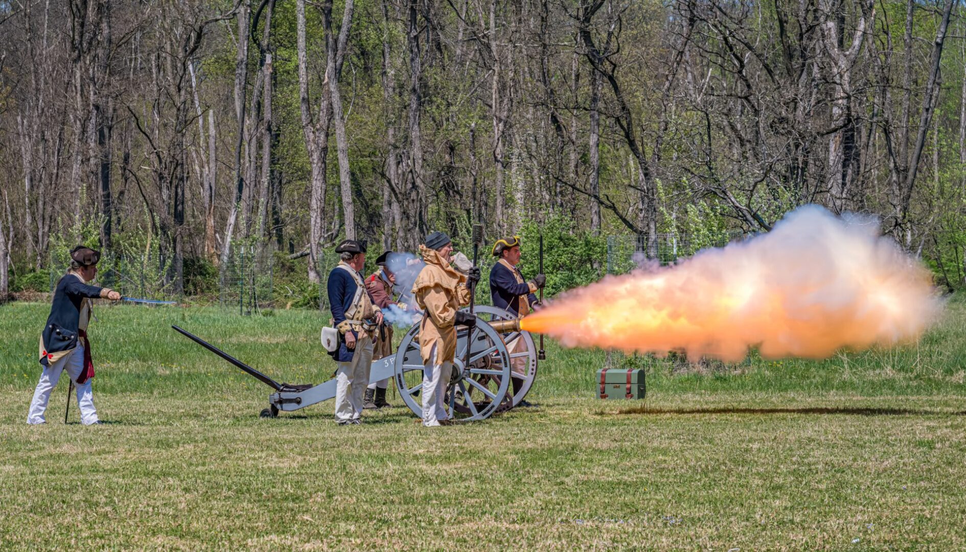 Reenactors firing a cannon with large flame